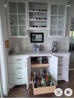 a kitchen with white cabinets and shelves filled with bottles