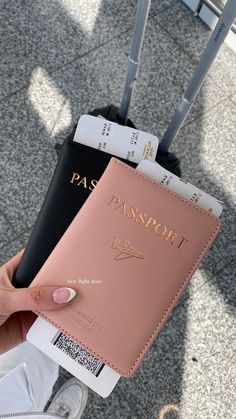 a person holding a pink passport case in front of their luggage on the ground at an airport