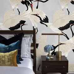 two white cranes flying over a bed in a room with blue pillows and gold accents