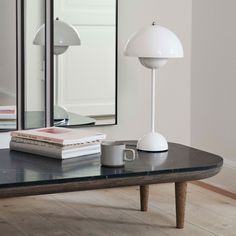 a table with a lamp, mirror and books on it in front of a door