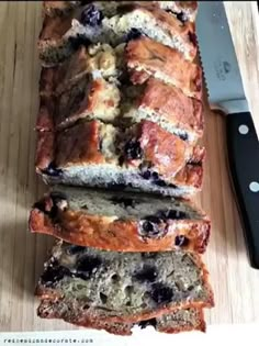 a loaf of blueberry bread sitting on top of a cutting board next to a knife