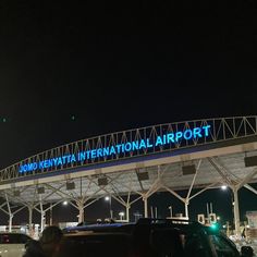 an airport terminal with cars parked under it at night