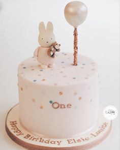 a birthday cake with a bunny holding a balloon on it's top and the word one written in white