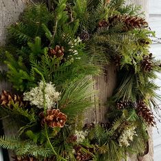 a wreath with pine cones and greenery is hung on a wooden door, ready to be decorated for the holiday season