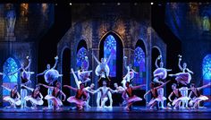 a group of ballet dancers on stage in front of stained glass windows with blue lights