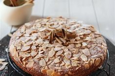 a cake sitting on top of a black plate next to a glass of milk and some almonds