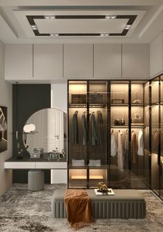 a walk - in closet is shown with clothes on shelves and an ottoman underneath the mirror