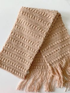 two crocheted scarfs sitting on top of a white table next to each other