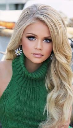 a barbie doll with long blonde hair wearing a green turtle neck sweater and flower earrings