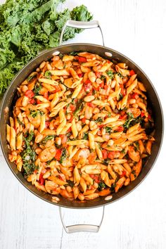 healthy chicken, sausage pasta with kale and white beans in a skillet on a table