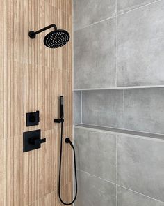 a shower head and hand shower in a bathroom with grey tiles on the back wall