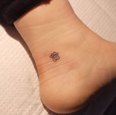 a small tattoo on the ankle of a woman's foot with an animal paw