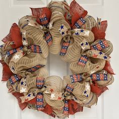 a patriotic wreath hanging on the front door with red, white and blue burlocks