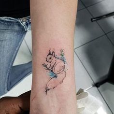 a small tattoo on the wrist of a woman's left arm, depicting a squirrel