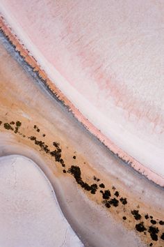 an aerial view of the water and sand at low tide beach, with black spots on it's surface