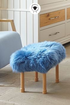 a blue stool sitting on top of a wooden floor next to a dresser and chair