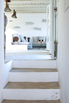 an open door leading to a living room with white walls and stairs that lead up to the second floor