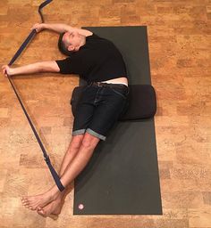 a man laying on a yoga mat with his legs crossed