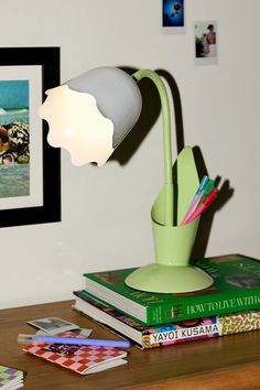 a green desk lamp sitting on top of a wooden table next to books and pictures