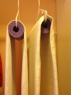 two white towels hanging from hooks in a bathroom