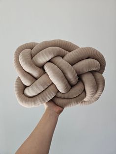 a hand holding up a large knot made out of fabric