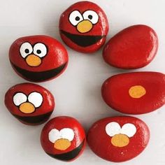 red painted rocks with yellow eyes and nose on white surface, arranged in the shape of an angry bird