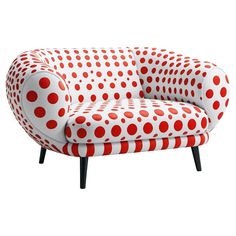 a red and white couch with polka dots on the back, sitting in front of a white background