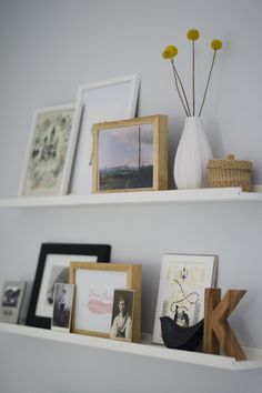 two white shelves with pictures and other items on them