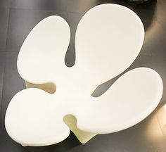 a large white flower shaped chair sitting on top of a black floor next to a lamp