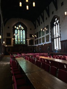 an empty room with tables and chairs in front of two large stained - glass windows