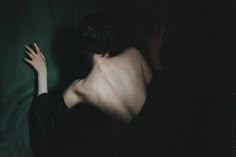 a nude woman in the dark with her hands up to her chest and arms outstretched