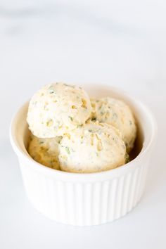 two scoops of ice cream in a white bowl on a white tablecloth with green sprinkles