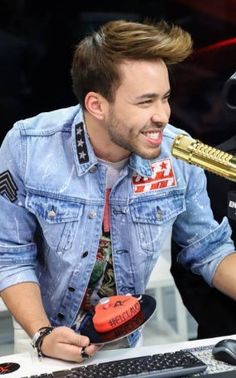 a man holding a microphone up to his mouth while sitting in front of a computer