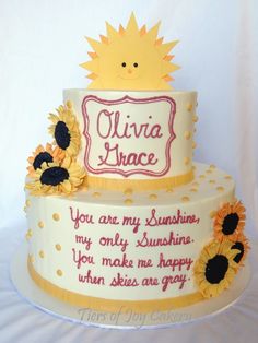 a three tier cake with sunflowers on the bottom and words written in white frosting