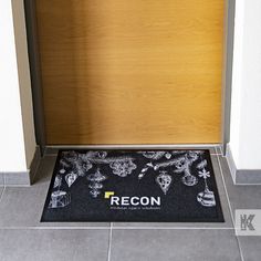 a door mat with the word recon on it in front of a wooden door