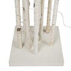 four white birch trees are standing on a square base with wires in the middle and one tree trunk sticking out of it's center