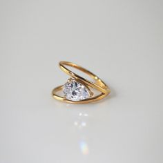 two gold rings with a single diamond in the middle, on a white table top