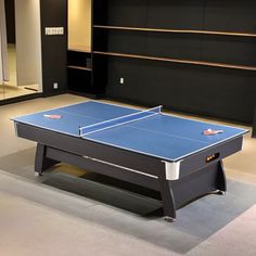 a ping pong table in an empty room with black walls and carpeting on the floor