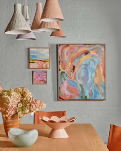 a wooden table topped with a vase filled with flowers next to two pictures on the wall