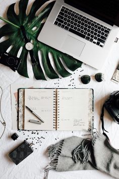 an open notebook sitting on top of a table next to a laptop computer and other items