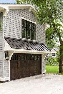 a gray house with two brown garage doors and a white trim on the side of it