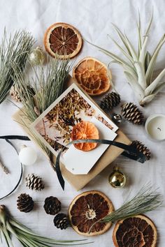 an assortment of dried fruits and pine cones on a table with candles, ornaments and decorations