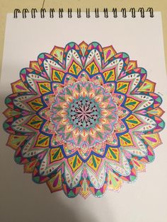 a drawing of a colorful flower on top of a white paper with colored pencils