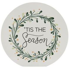 a white plate with the words tis the season written in black ink on it, surrounded by greenery