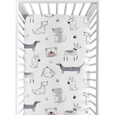 a white crib with dogs and paw prints on the sheet in front of it