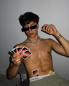 a shirtless man wearing sunglasses and playing cards