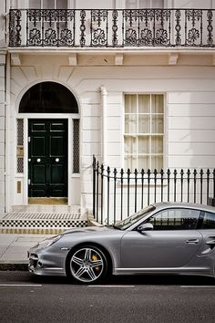 a silver sports car parked in front of a white building