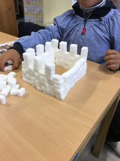 a young boy sitting at a table with white blocks on it