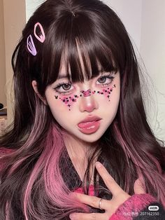 a girl with pink and black makeup is holding her hand up to her face while posing for the camera