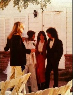 four people standing around each other in formal wear